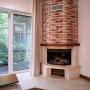 В гостиной установлен угловой дровяной камин с дымоходом, отделанным "под кирпич"