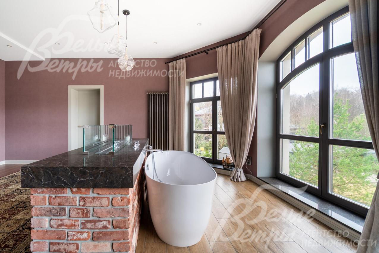 За перегородкой у окна находится литая отдельно стоящая ванна, на перегородке - биокамин