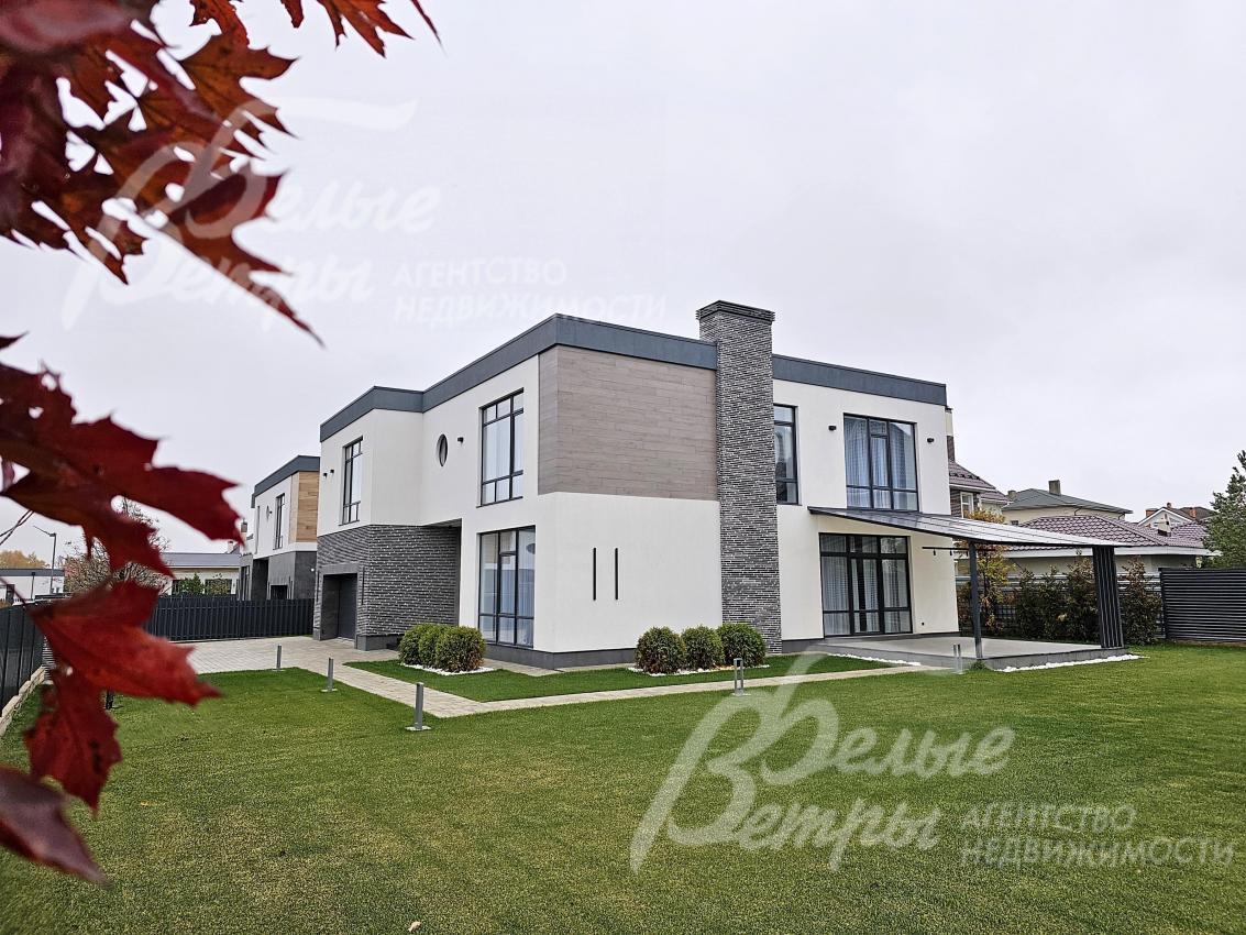 Дом стоит на просторном зелёном участке с высаженным газоном и вымощенными дорожками