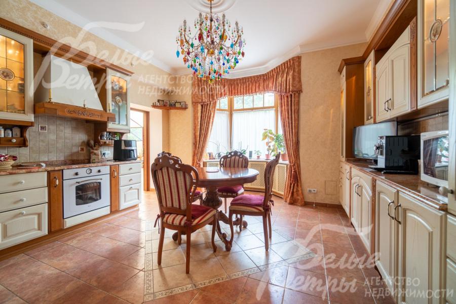 Кухня полностью меблирована итальянским гарнитуром по индивидуальному проекту из массива дерева со встроенной техникой и мраморной столешницей, обеденной группой