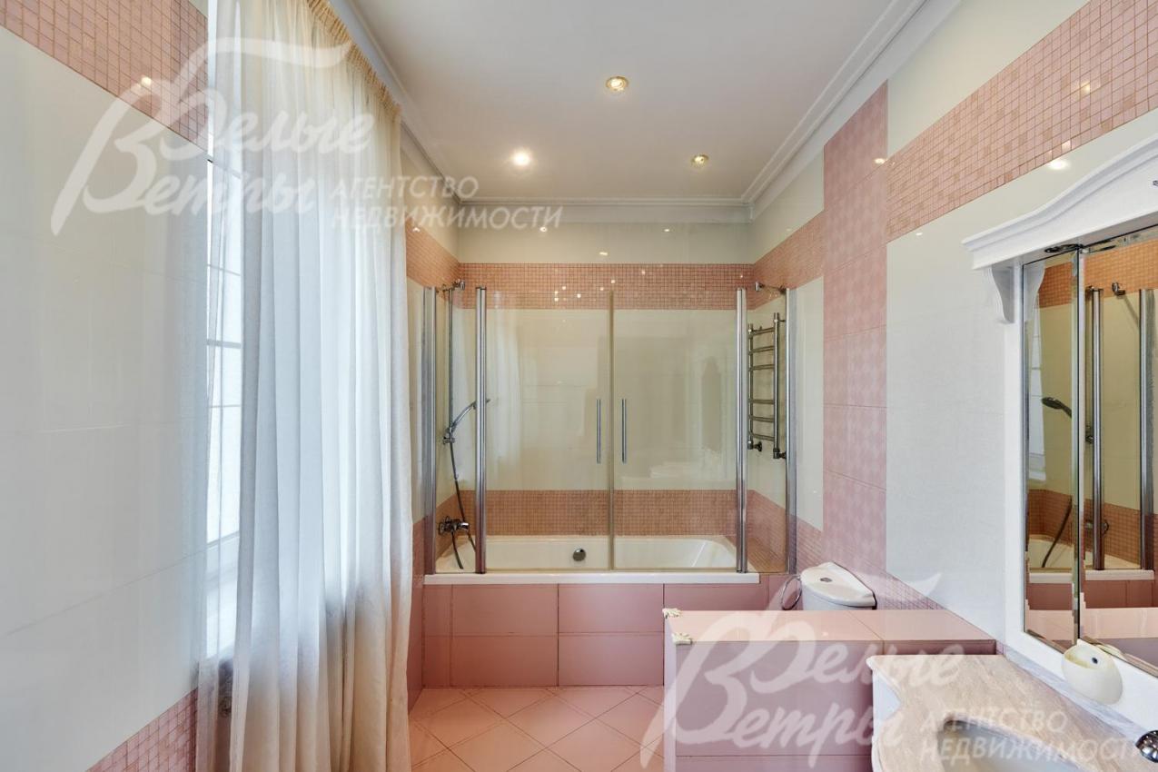 Один из санузлов на втором этаже в светло-розовых тонах с ванной со стеклянной ширмой