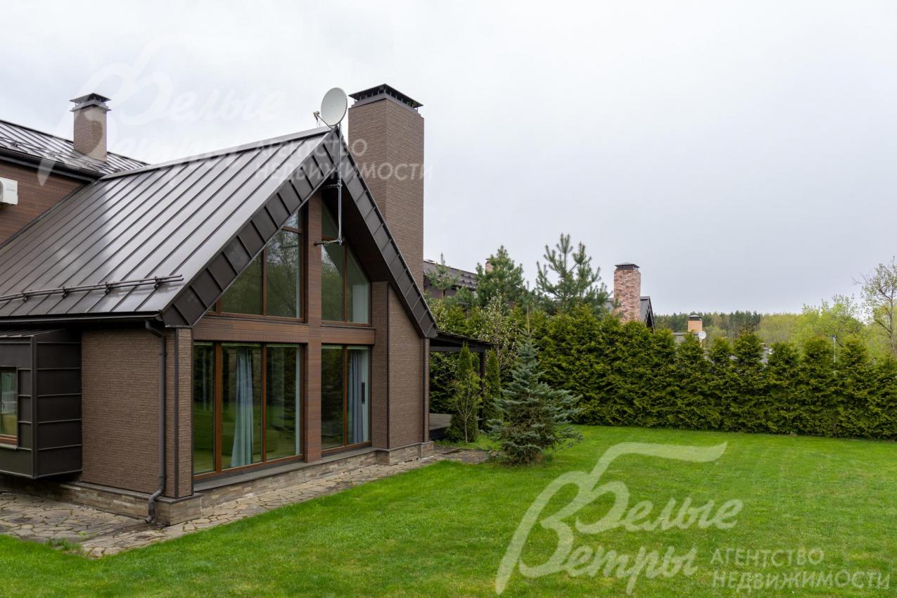 Стильный фасад с комбинированной облицовкой: на стенах - фиброцементные панели под дерево и кирпич, цоколь - песчаник