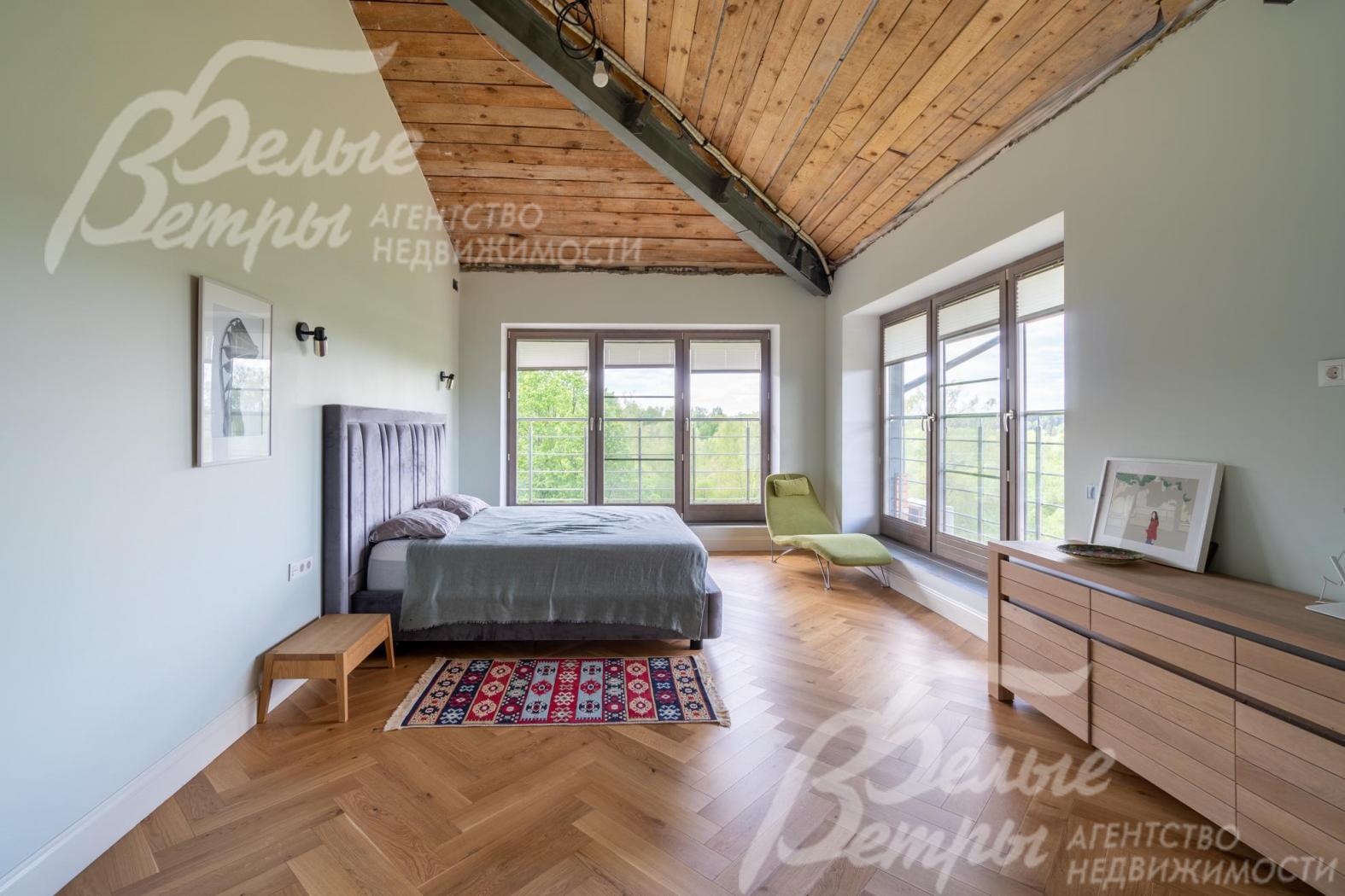 Первая мастер-спальня на втором этаже с большими окнами в пол, потолками из гипсокартона, отделанными деревом