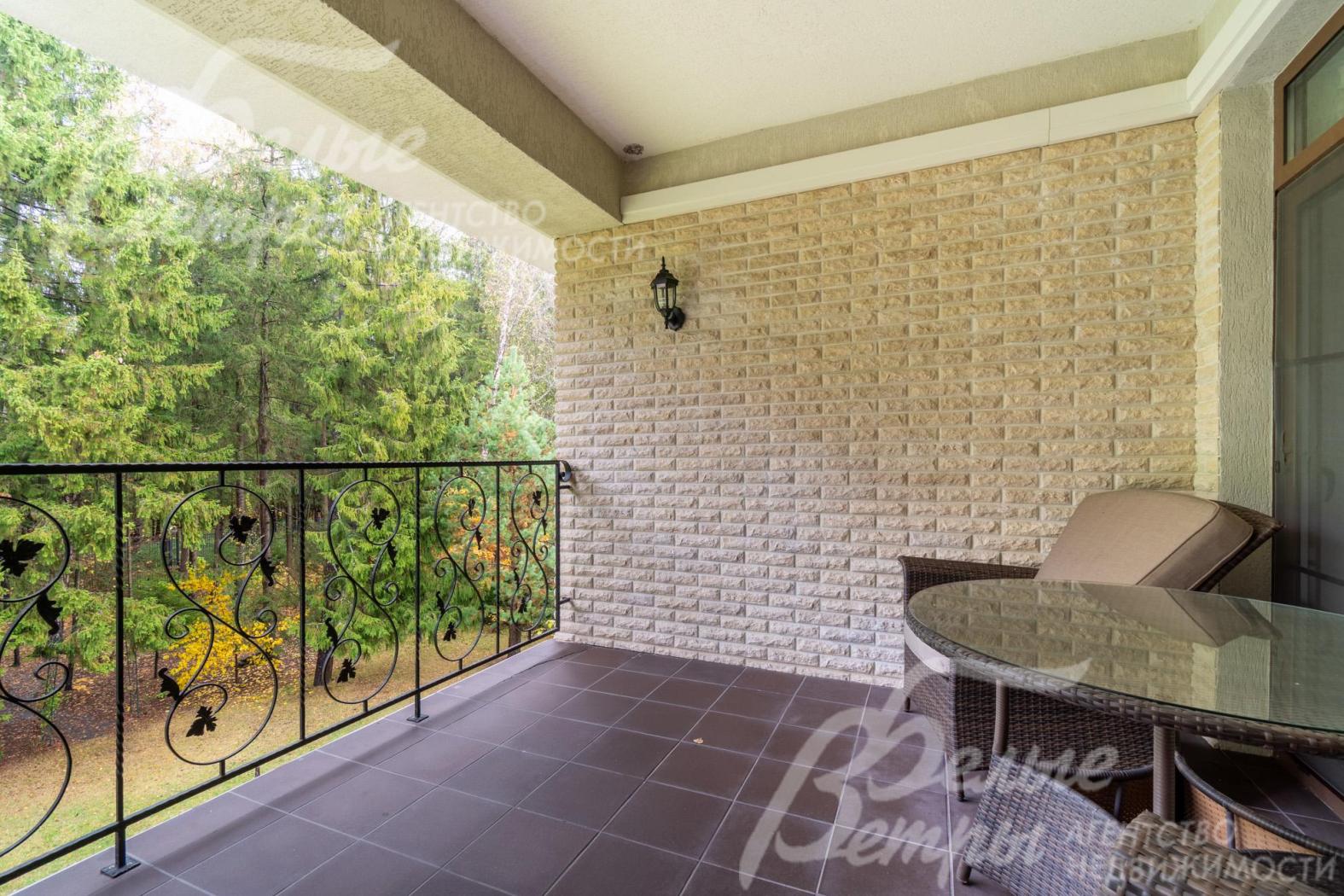 На лоджии установлена садовая мебель, украшает лоджию кованое ограждение