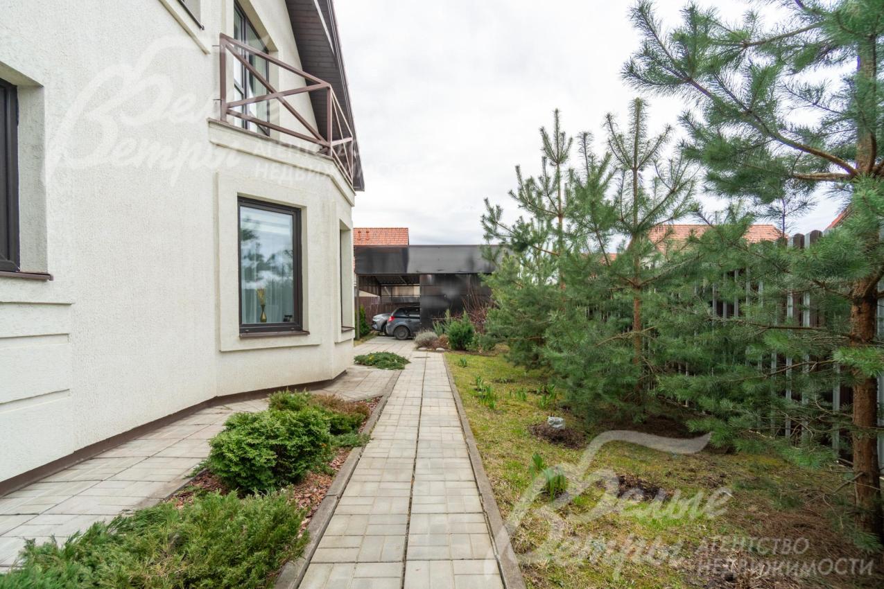 Вокруг дома выполнена отмостка, дорожки выложены крупной плиткой, вдоль забора высажены ели