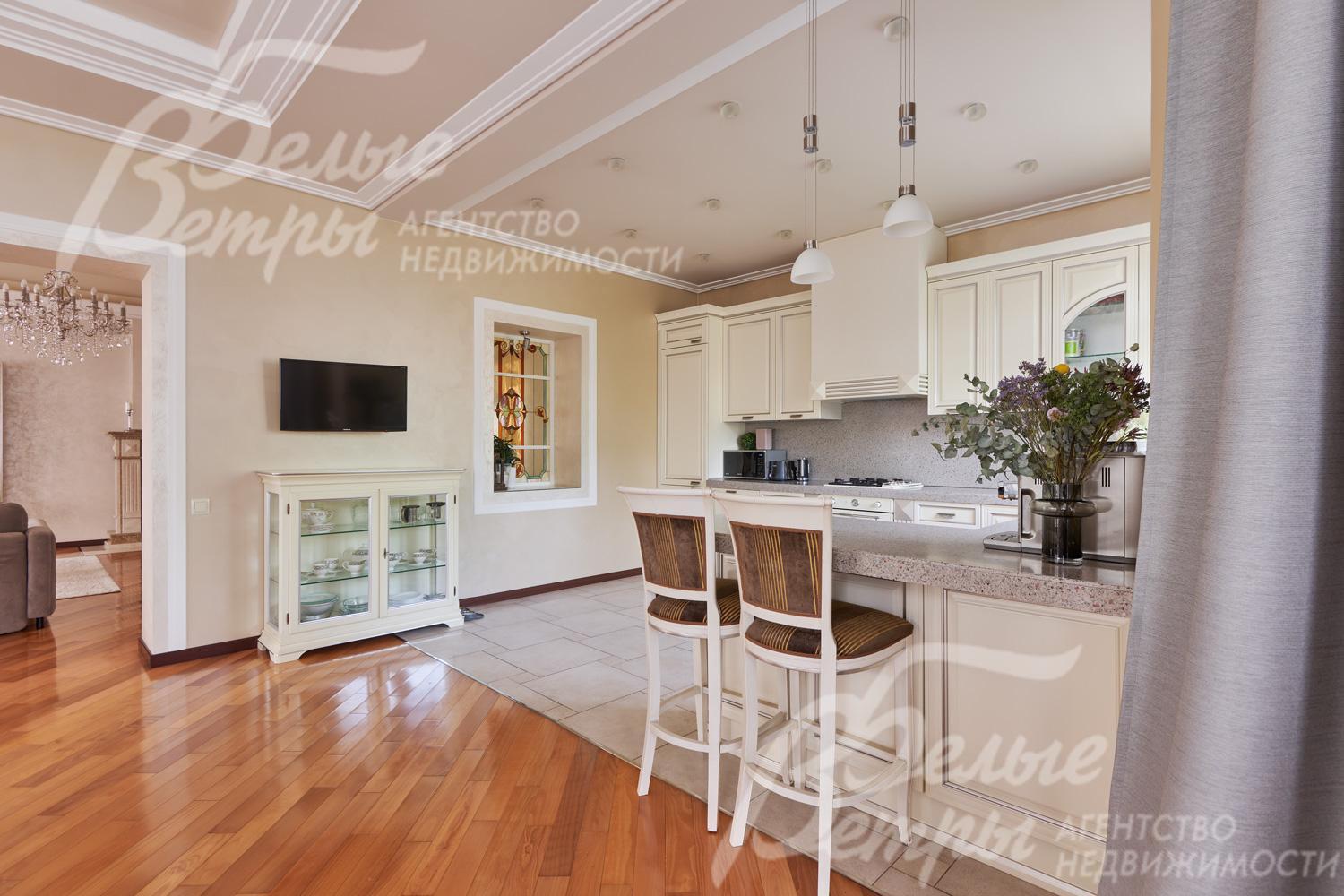 Кухня-столовая с отделкой в светло-бежевых тонах с многоуровневыми потолками и стильной системой освещения