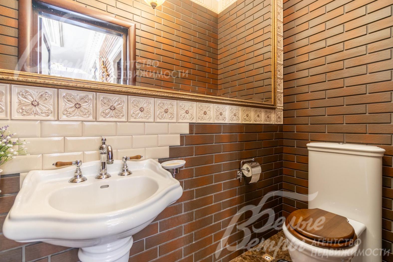 Гостевой санузел на первом этаже с большим зеркалом, стены отделаны клинкерной плиткой