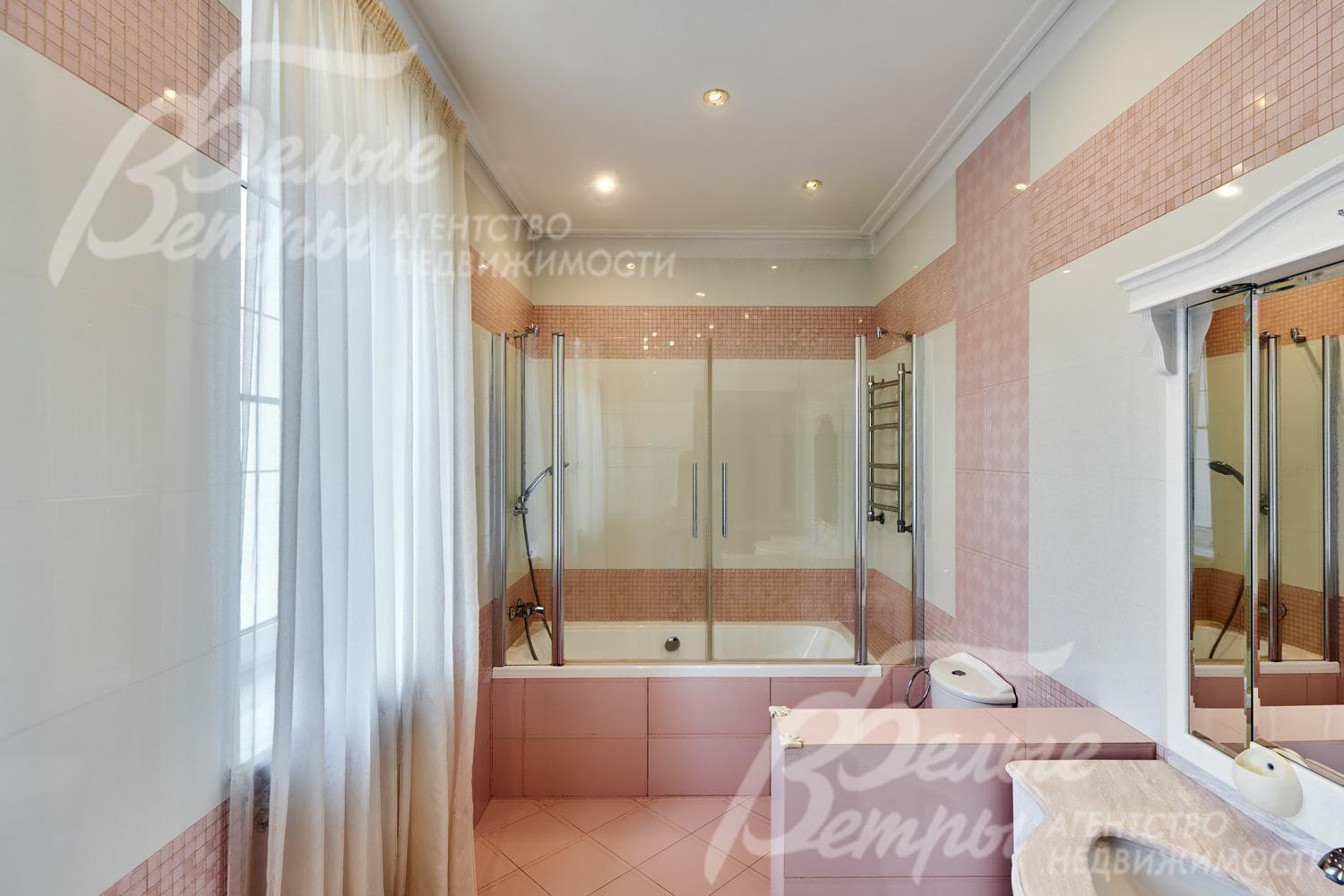 Один из санузлов на втором этаже в светло-розовых тонах с ванной со стеклянной ширмой