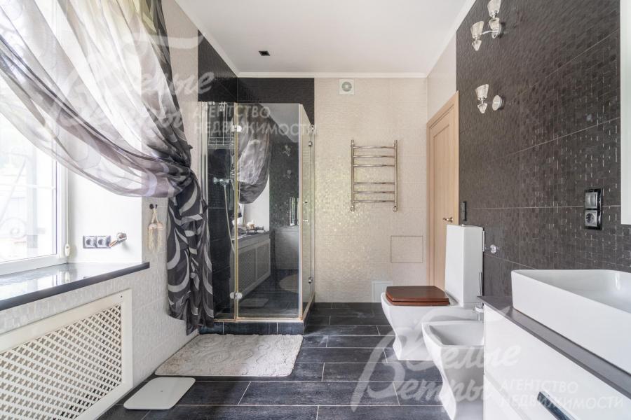 Санузел с большим окном, стены отделаны итальянской плиткой, на полу - керамогранит с подогревом