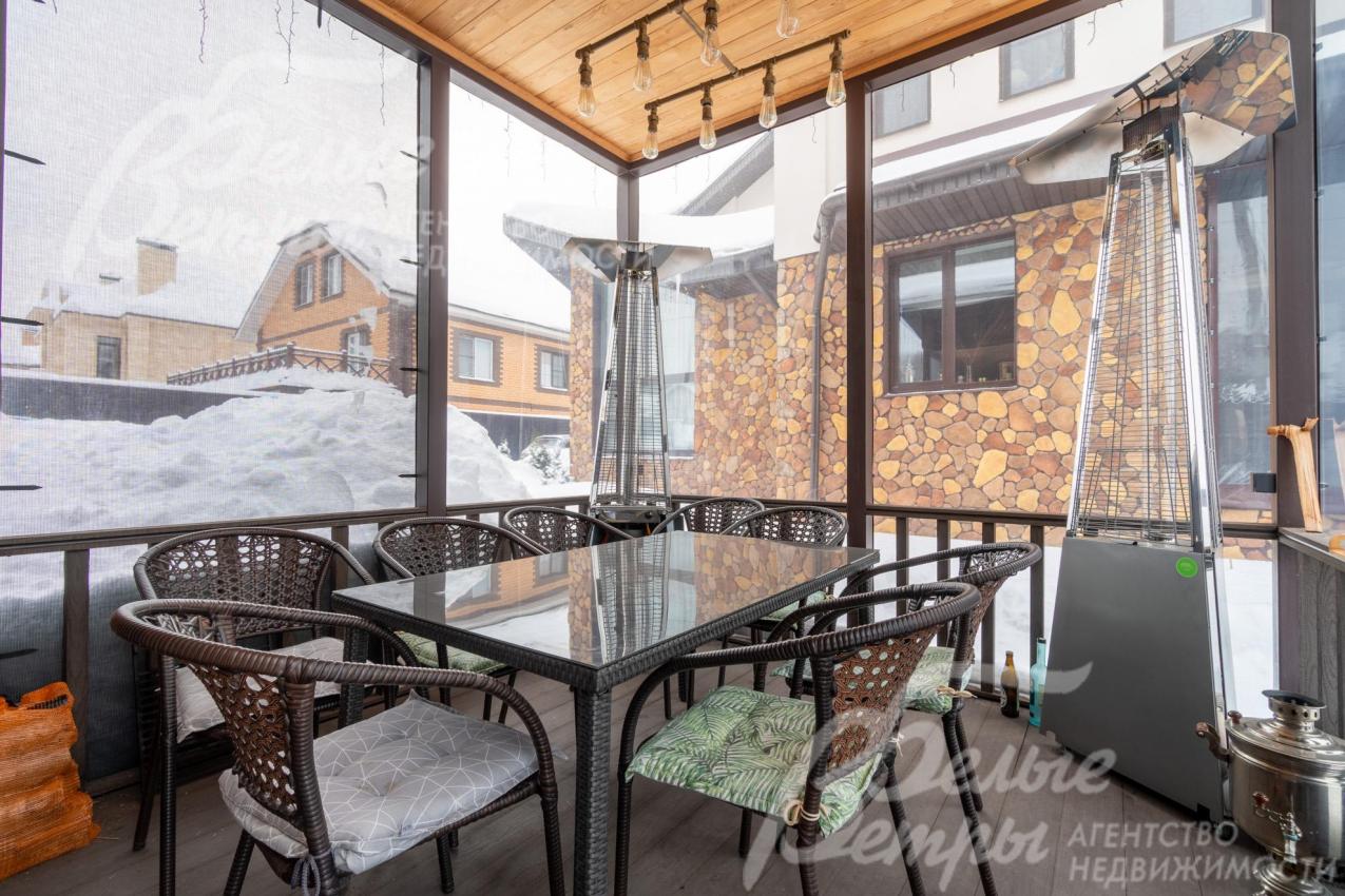 В беседке установлена садовая мебель, конструкция закрывается мягким стеклом