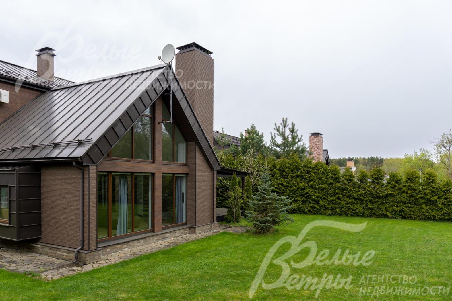 Стильный фасад с комбинированной облицовкой: на стенах - фиброцементные панели под дерево и кирпич, цоколь - песчаник