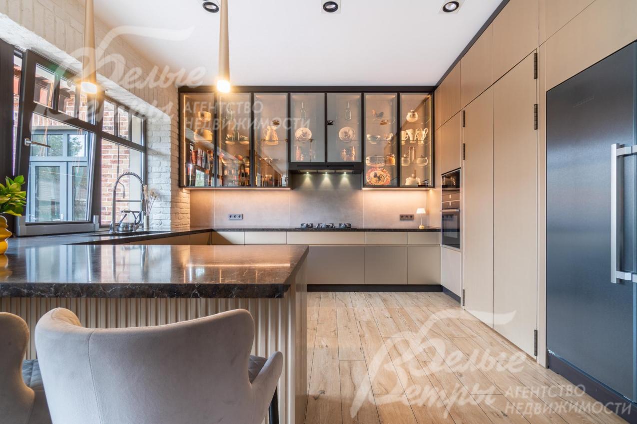 На кухне установлен премиальный гарнитур «Джулия Новарс» с высокими шкафами-витринами с эффектной подсветкой