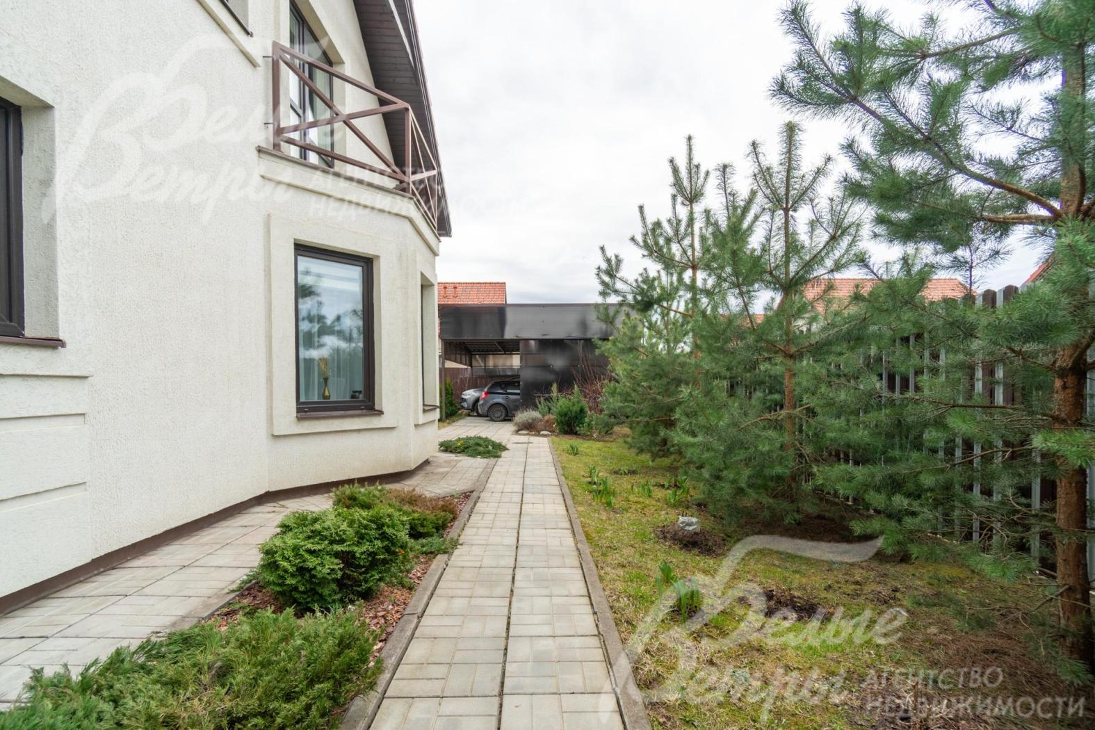 Вокруг дома выполнена отмостка, дорожки выложены крупной плиткой, вдоль забора высажены ели