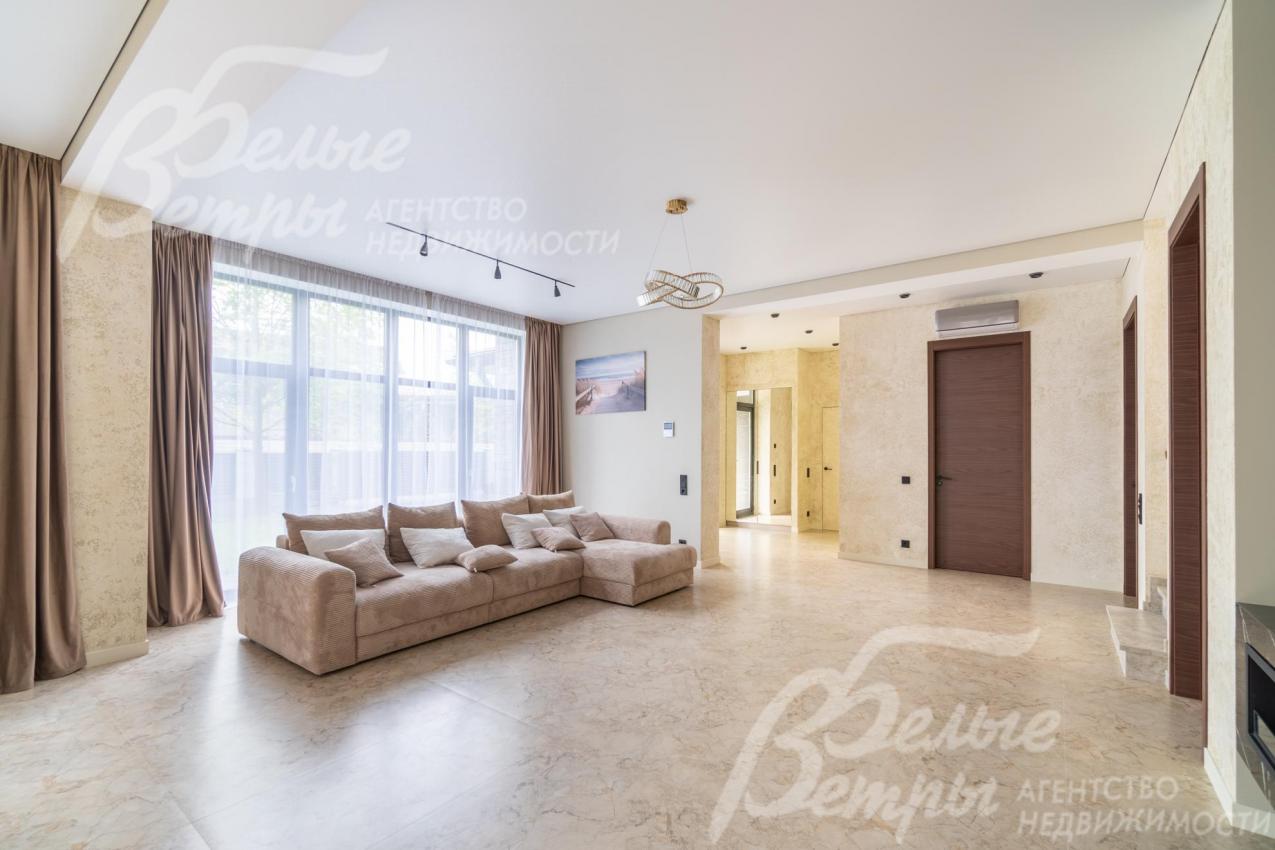 Светлая гостиная с панорамным остеклением, высоким потолком и трековым освещением