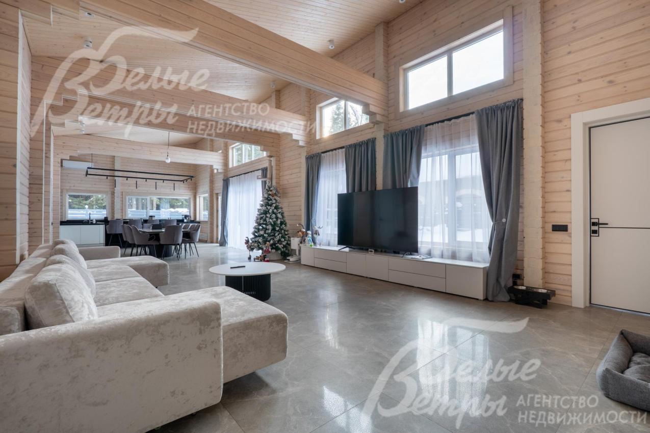 Гостиная - двухсветная, в ней установлен уютный диван и телевизор с акустической системой