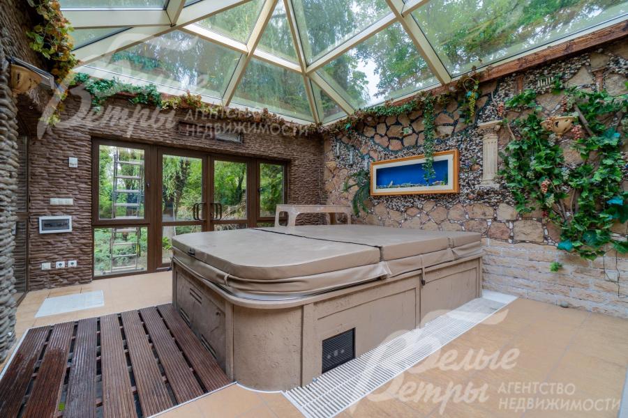 Зимний сад со стеклянной крышей и стенами, отделанными "под камень"