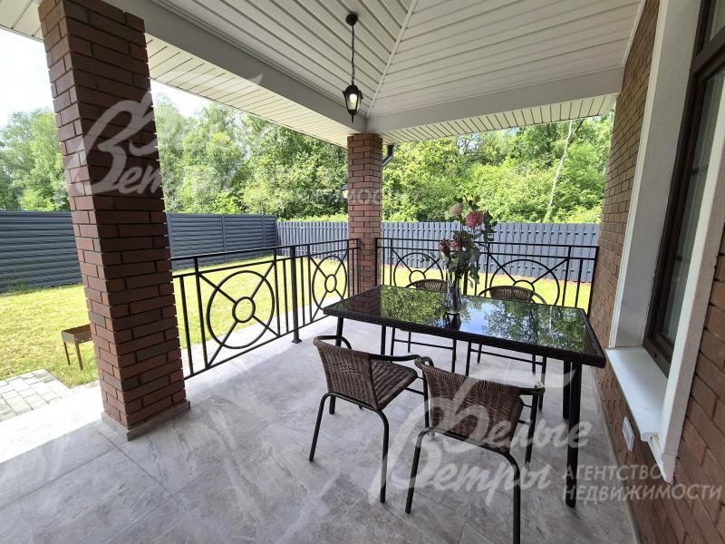 Уютная крытая терраса с видом на участок и лес.