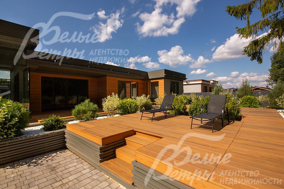 На подиумной террасе стоит садовая мебель