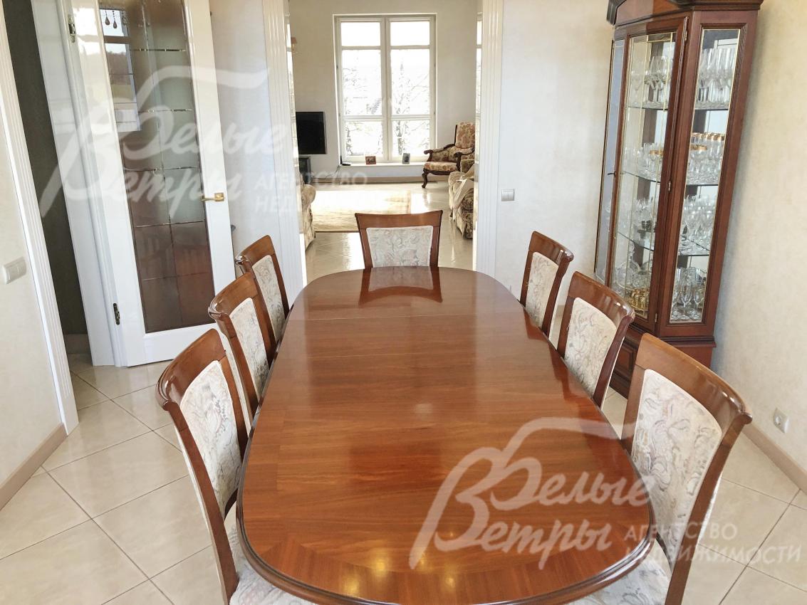 В столовой большой обеденный стол из массива на 8 персон со стульями