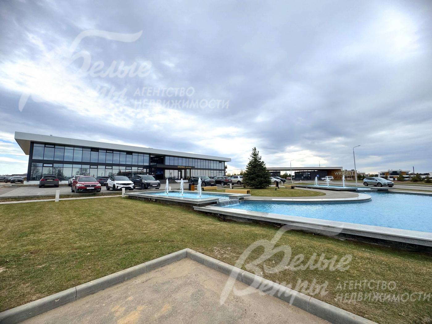 Территория коттеджного посёлка. Административное здание, гостевая парковка и рекреационная зона с большим фонтаном