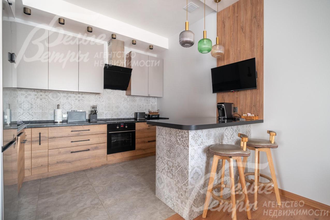 На кухне - удобный гарнитур с полубарным островом и большим холодильником Hisense