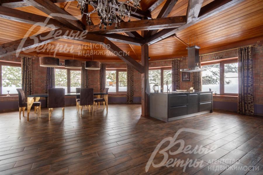 Потолок гостиной‑кухни‑столовой - с балочной потолочной системой. В зоне столовой расположен большой обеденный стол