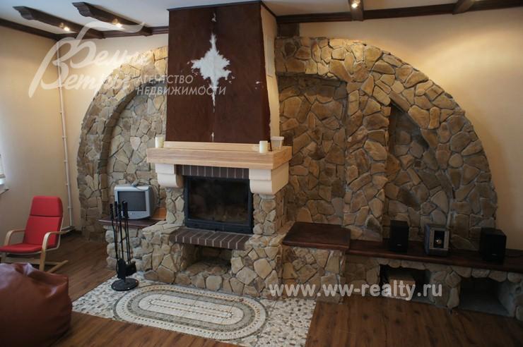 Роскошный камин, отделанный натуральным камнем и звериными шкурами в гостиной