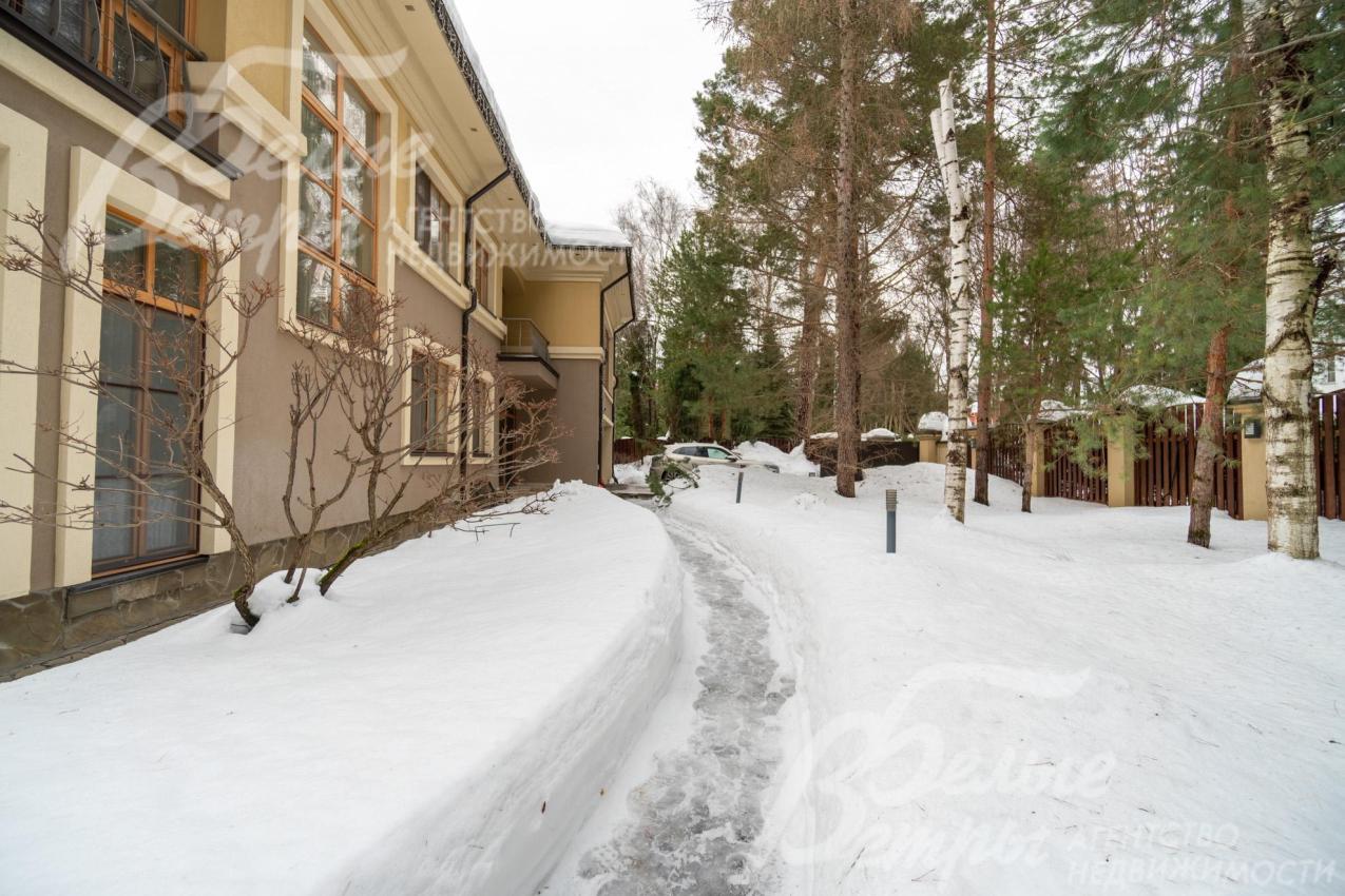 На участке высажены туи и кусты можжевельника, проложены дорожки, установлены светильники и скамейки