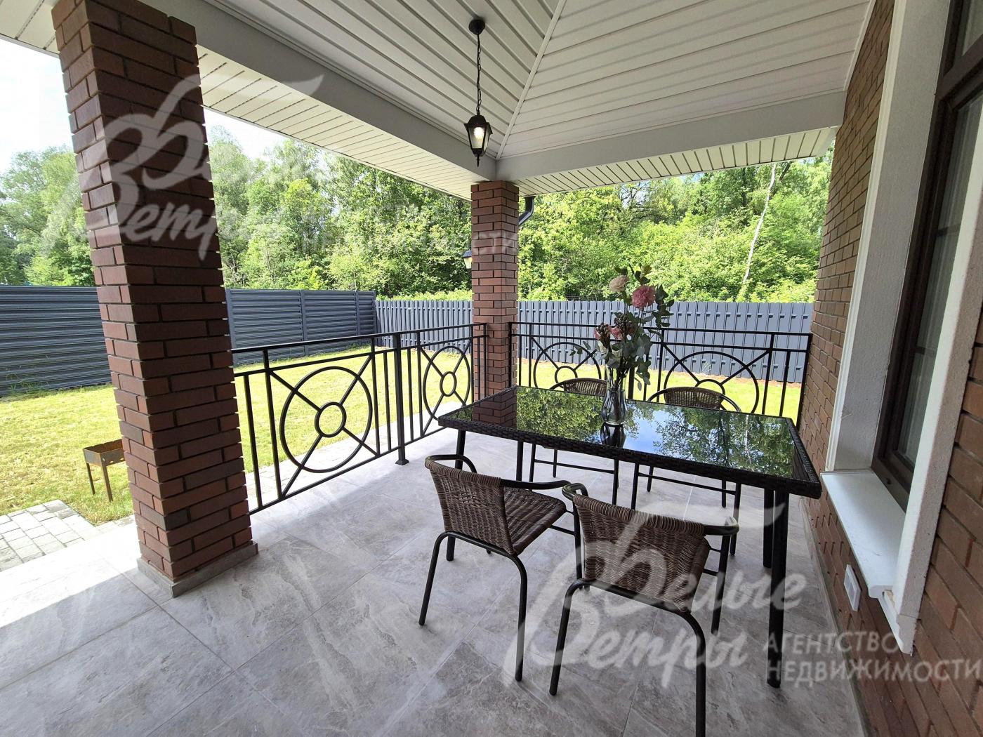 Уютная крытая терраса с видом на участок и лес.