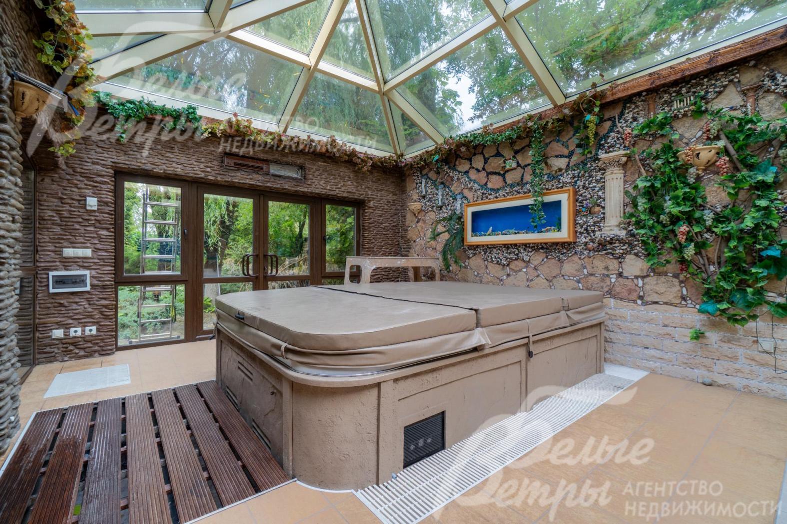 Зимний сад со стеклянной крышей и стенами, отделанными "под камень"