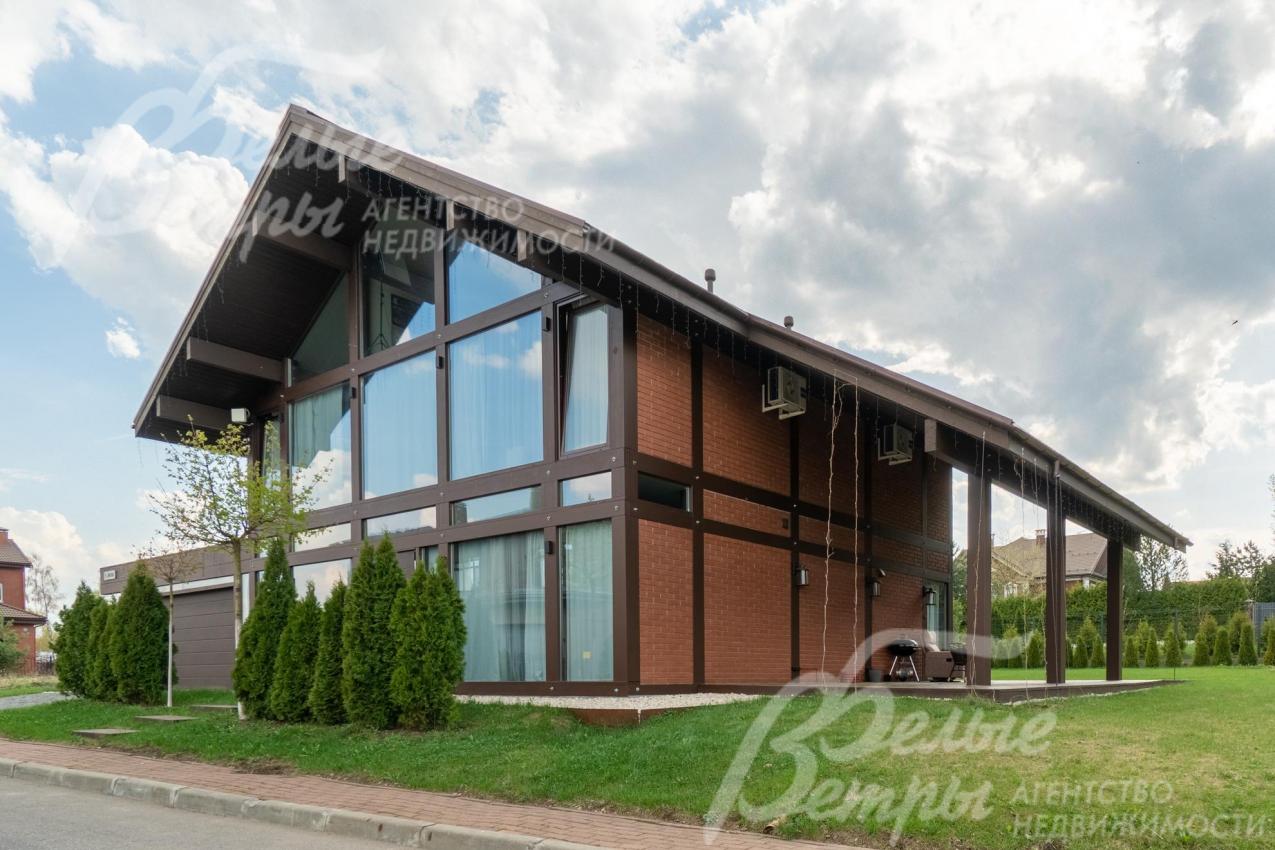 Фасадное остекление выполнено из закалённого стекла: в окнах отражается небо, зелень участка