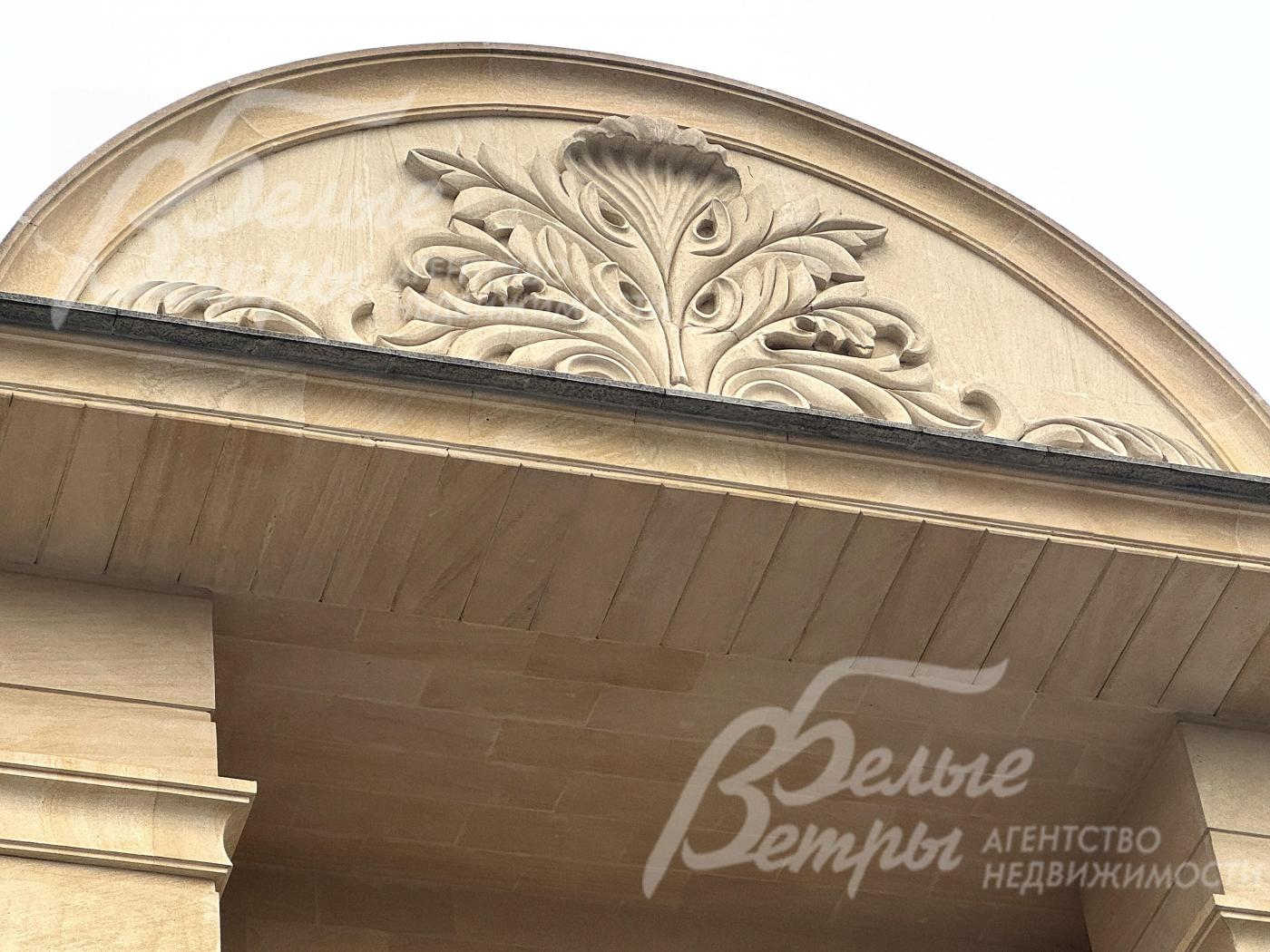 В центре фасада расположено декоративное панно ручной работы из камня