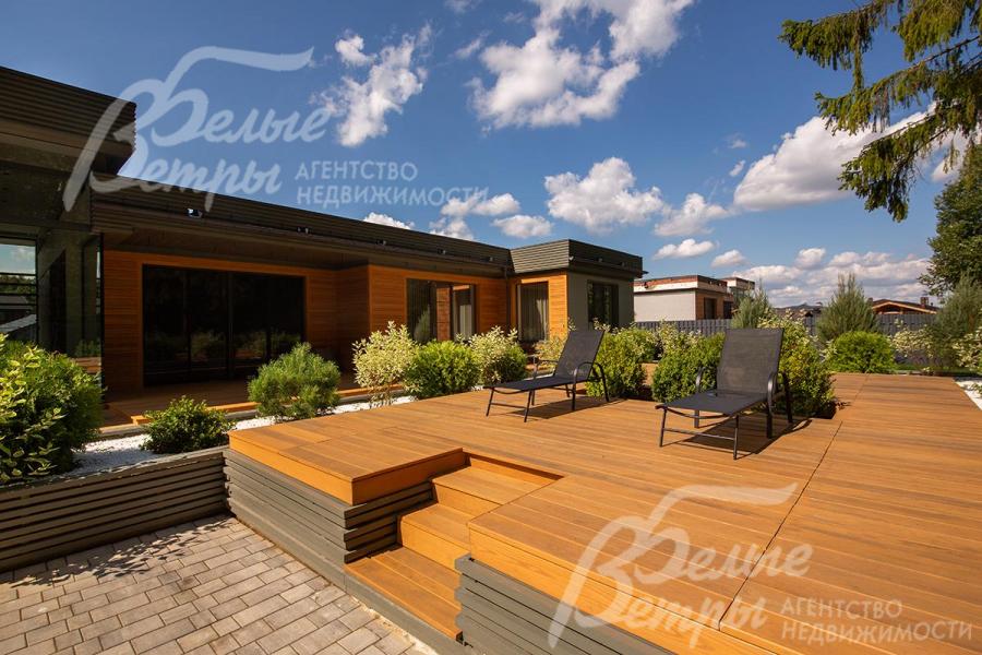 На подиумной террасе стоит садовая мебель