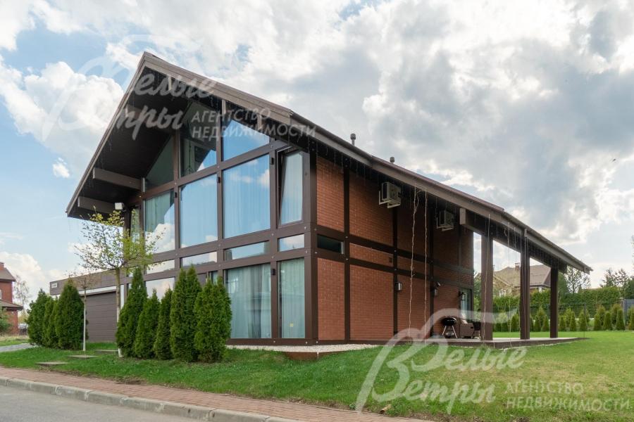 Фасадное остекление выполнено из закалённого стекла: в окнах отражается небо, зелень участка