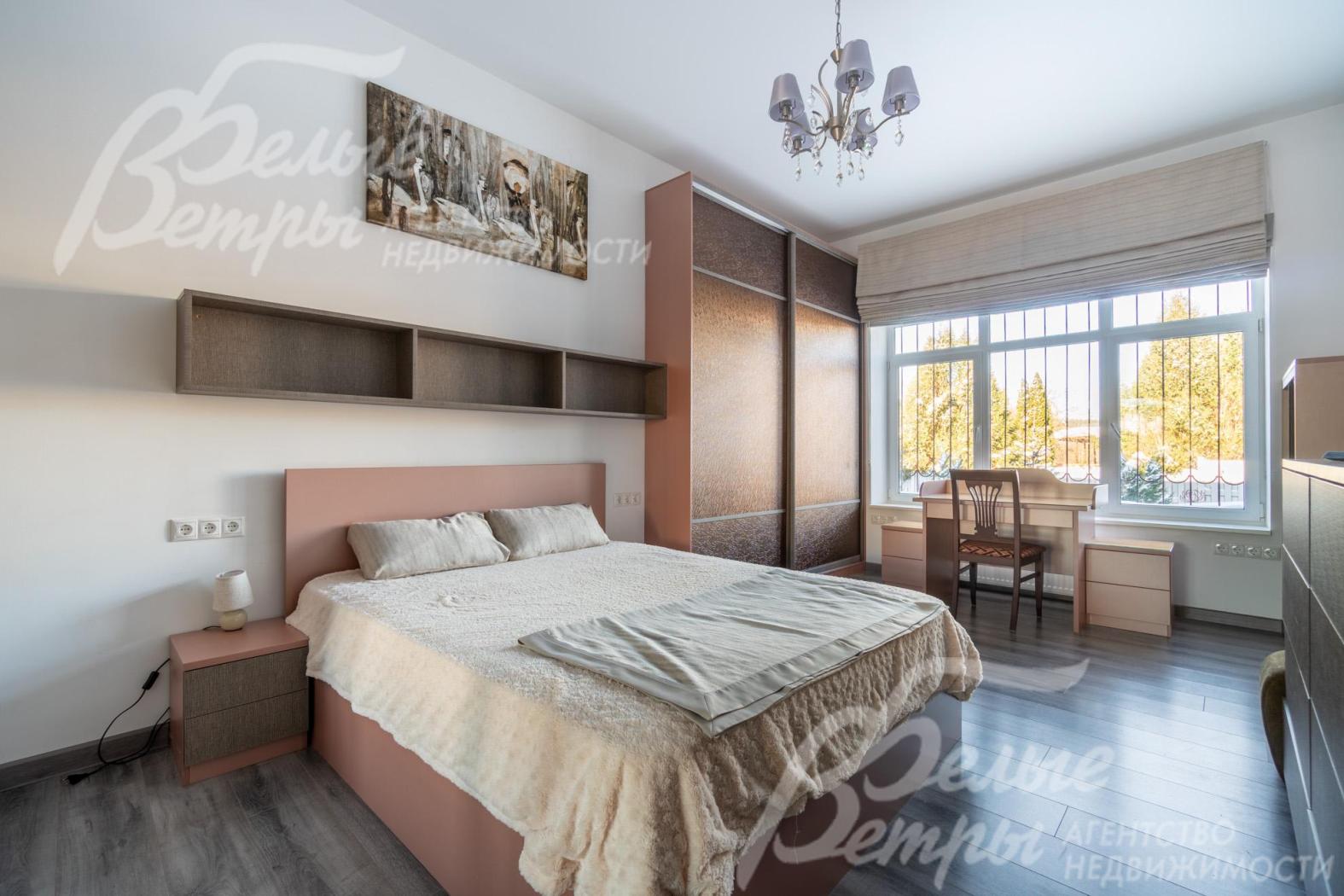 Мастер-спальня с большой кроватью, шкафами и рабочем местом расположена на первом этаже