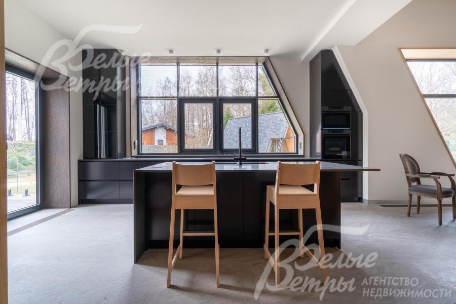 В стильной контрастной отделке кухни - выразительные графитовые и чёрные акценты в оконных рамах, из больших окон открывается красивый вид на участок 