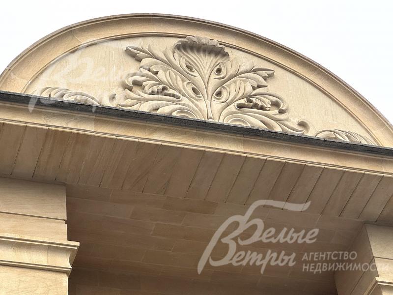 В центре фасада расположено декоративное панно ручной работы из камня