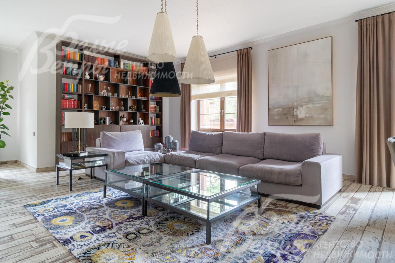 В гостиной - уютная диванная зона с мини-библиотекой. Дом украшают живописные полотна известных художников.