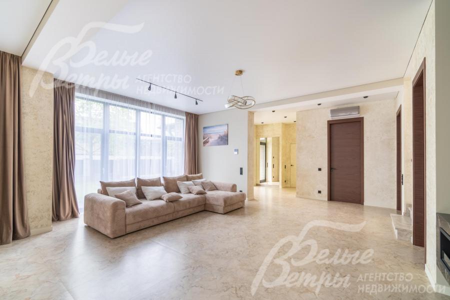 Светлая гостиная с панорамным остеклением, высоким потолком и трековым освещением