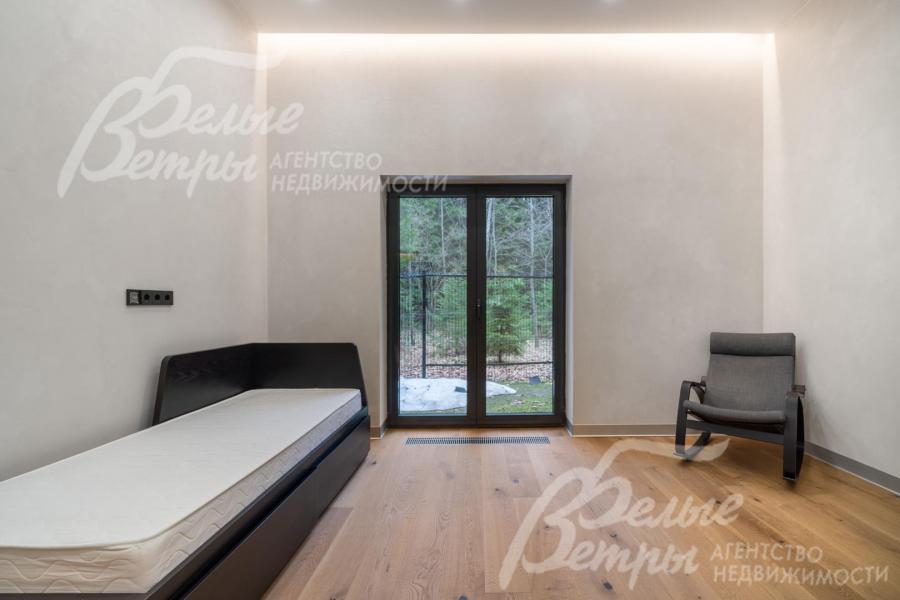 Одна из спален находится на первом этаже с большим окном в пол и эффектным скрытым освещением