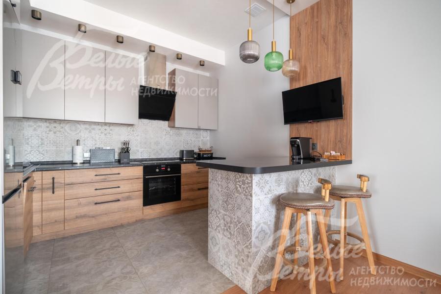 На кухне - удобный гарнитур с полубарным островом и большим холодильником Hisense