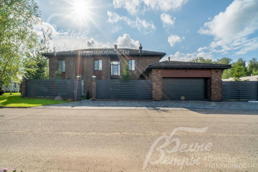 Фасадный забор  - в стиле дома, на кирпичных столбах и фундаменте, заполнение – покрашенная переплетенная доска. 