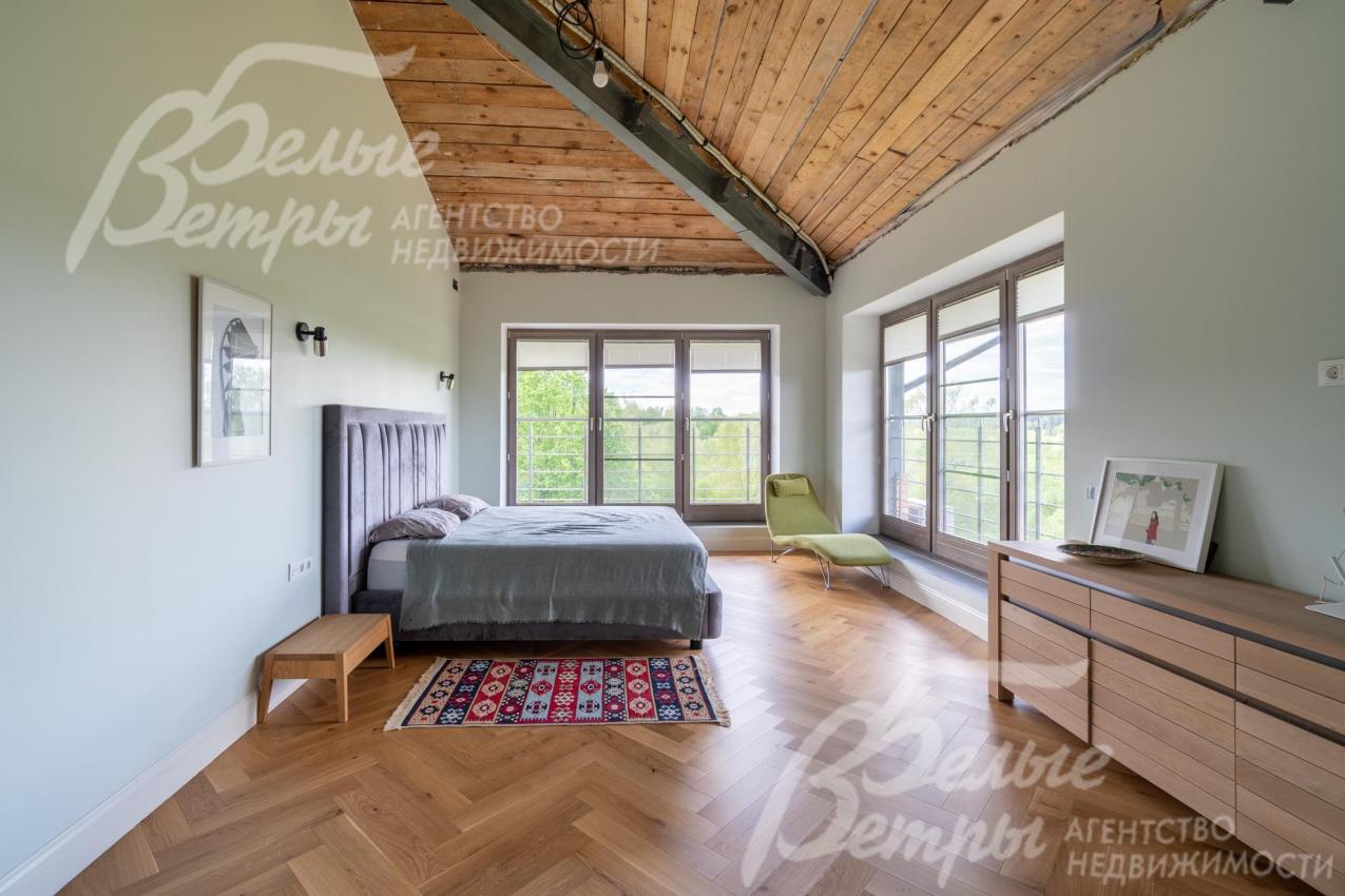 Первая мастер-спальня на втором этаже с большими окнами в пол, потолками из гипсокартона, отделанными деревом