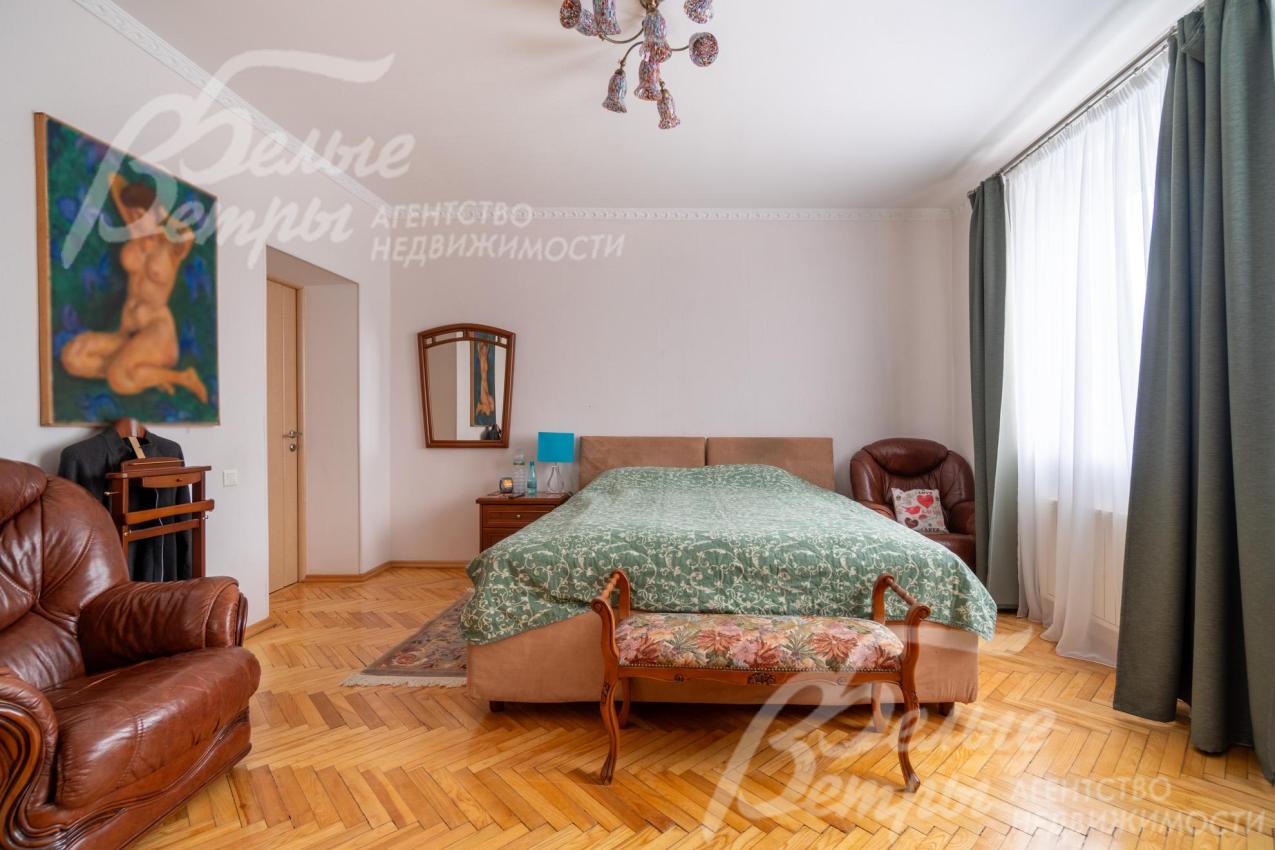 Спальня на втором этаже с большим окном, на полу - паркет, в интерьере - большая кровать и кожаные кресла