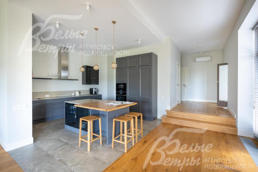 Кухня с гарнитуром и островом отделена от пространства гостиной-столовой контрастным полом и стенами без дверей