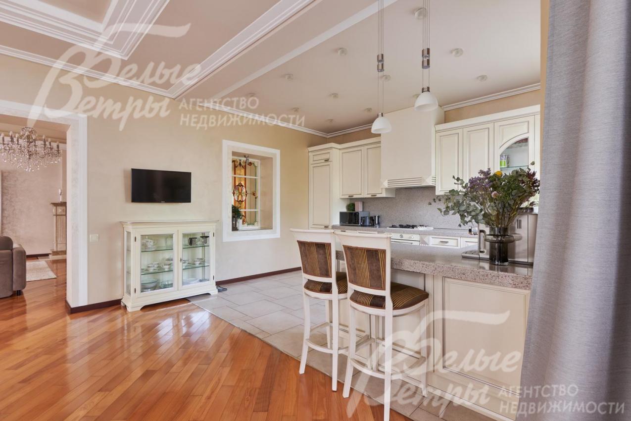 Кухня-столовая с отделкой в светло-бежевых тонах с многоуровневыми потолками и стильной системой освещения