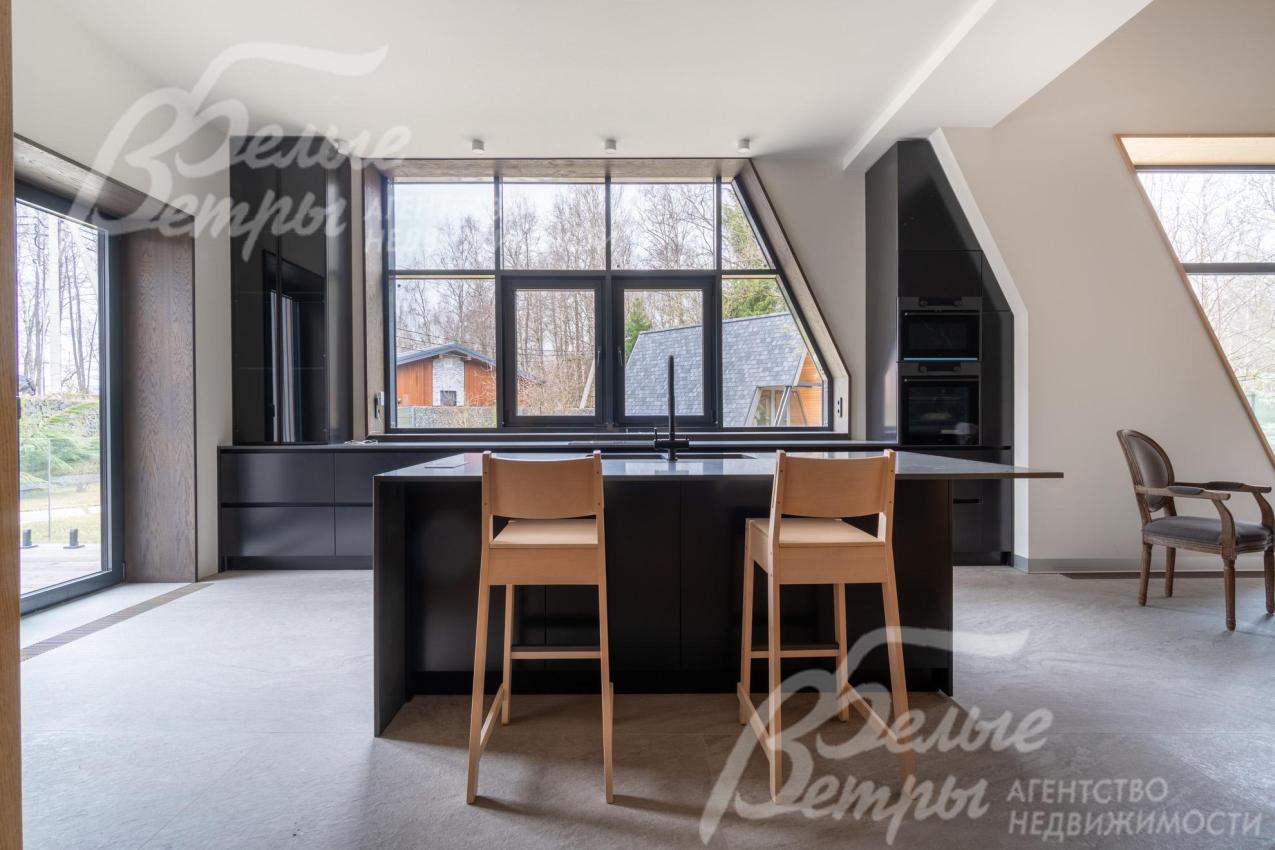 В стильной контрастной отделке кухни - выразительные графитовые и чёрные акценты в оконных рамах, из больших окон открывается красивый вид на участок 