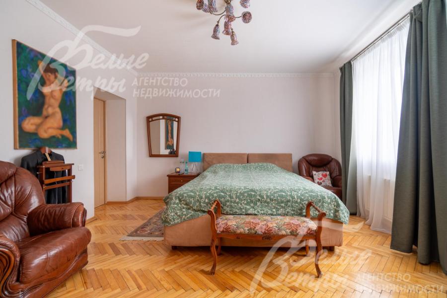 Спальня на втором этаже с большим окном, на полу - паркет, в интерьере - большая кровать и кожаные кресла