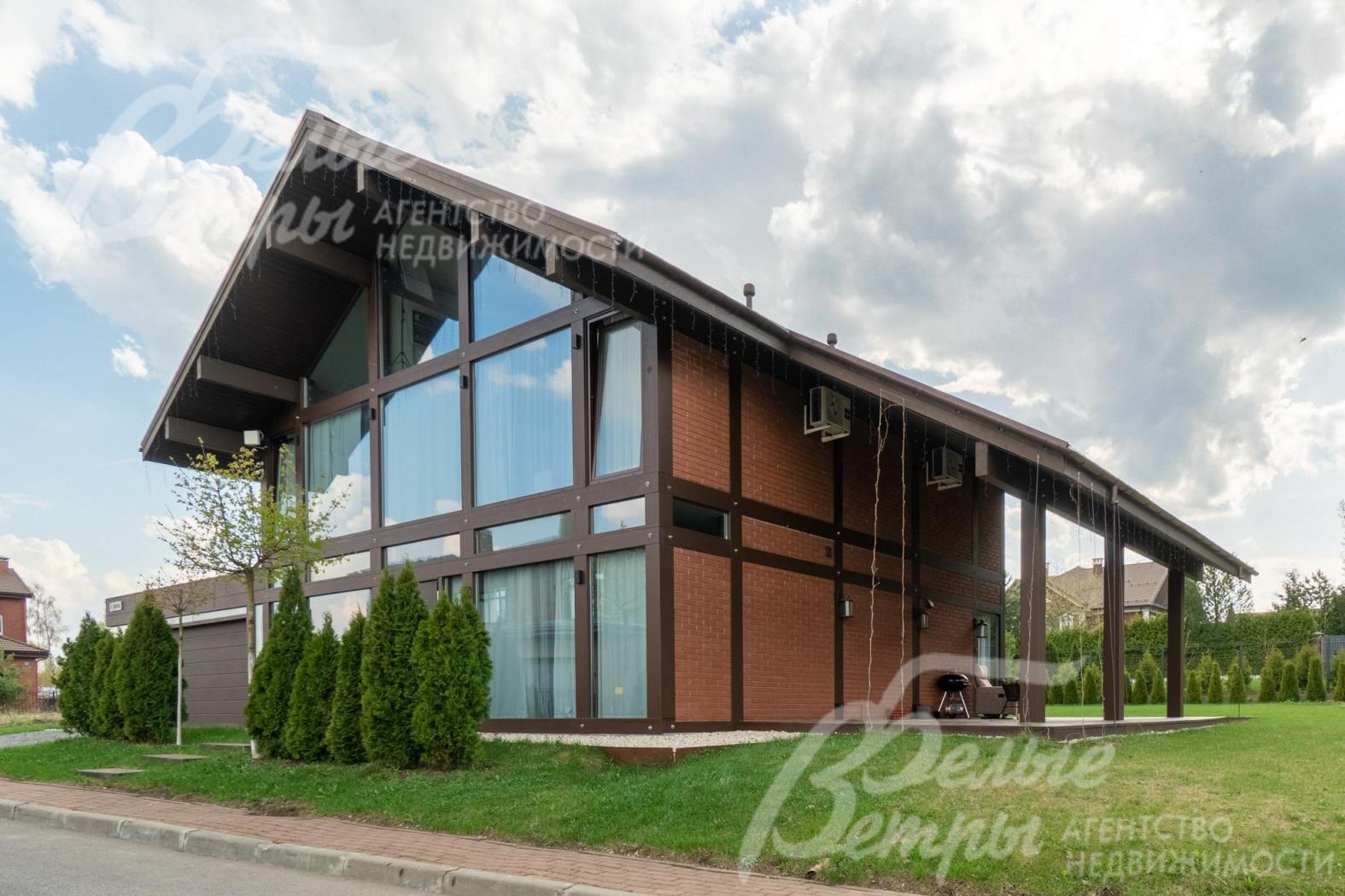 Фасадное остекление выполнено из закалённого стекла: в окнах отражается небо, зелень участка