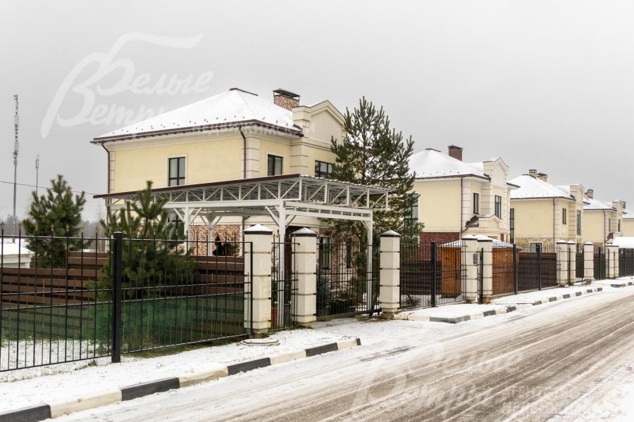 Территория огорожена: фасадный забор — металлический, высотой 2 м, в единой стилистике посёлка на бетонных столбах и фундаменте